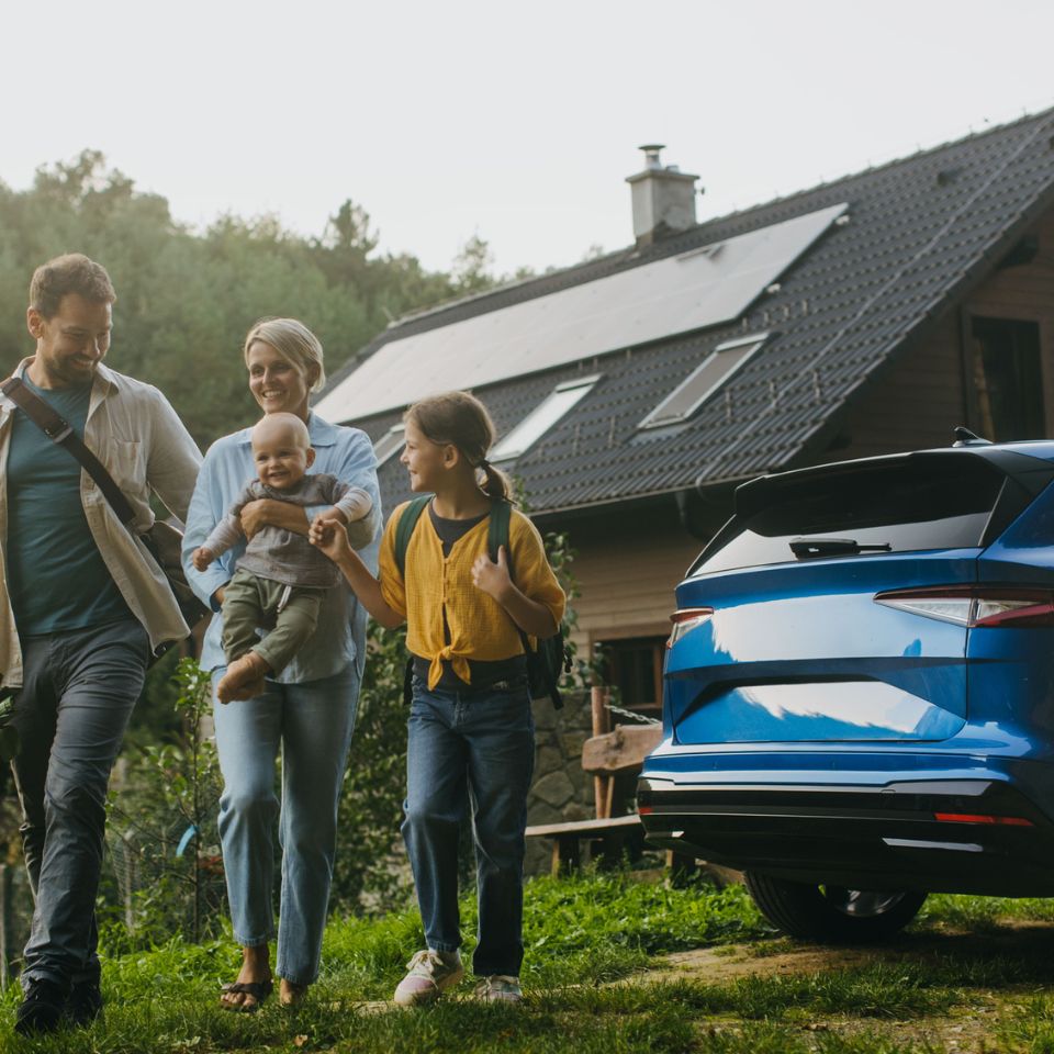 Family with an electric car outside a home with solar panels